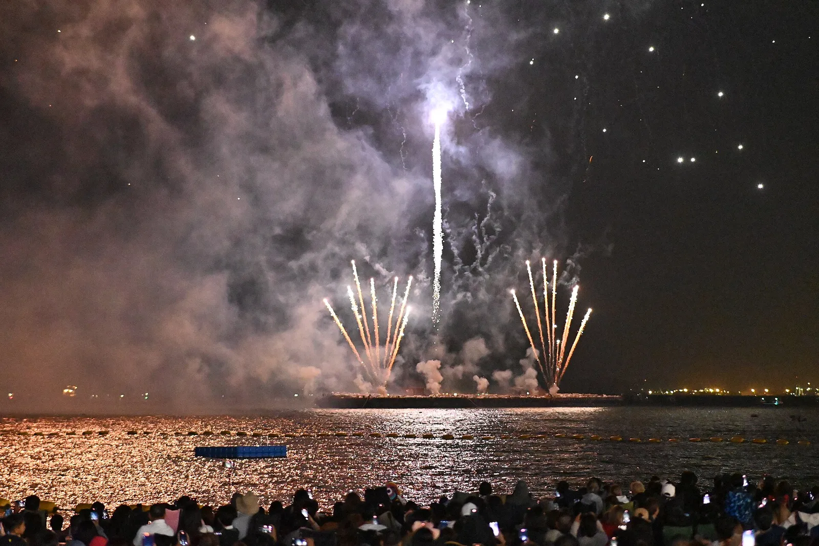Uno spettacolo di fuochi d'artificio sopra l'acqua con la folla che assiste